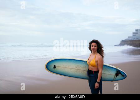 Giovane donna sicura di sé con tavola da surf in spiaggia in vacanza Foto Stock