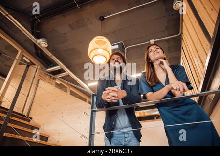 Uomini d'affari contemplativi in piedi vicino ai gradini in ufficio Foto Stock