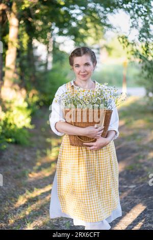 Donna sorridente con cesto di fiori bianchi Foto Stock