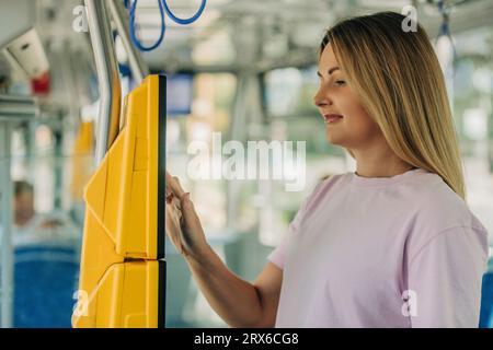 Giovane donna che compra il biglietto dalla macchina in treno Foto Stock