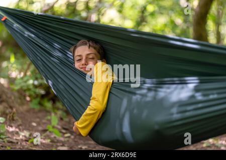 Ragazzo carino che si rilassa sull'amaca, giorno d'estate Foto Stock