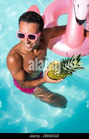 Uomo felice che tiene ananas e nuota in acqua Foto Stock