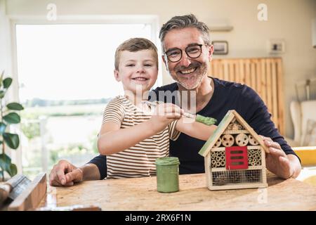 Felice nipote che dipinge la casa modello dal nonno a casa Foto Stock