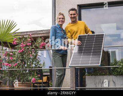 Coppia che installa il pannello solare sul balcone Foto Stock