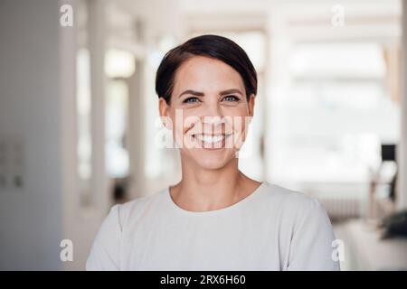 Donna d'affari felice con i capelli corti sul posto di lavoro Foto Stock