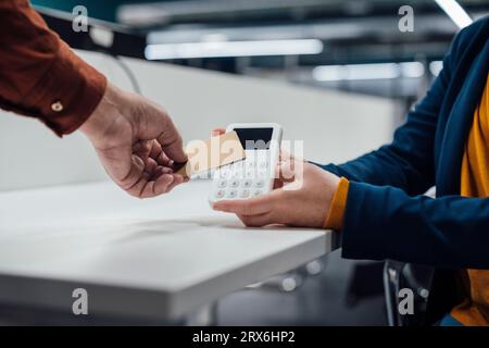 Mano di un uomo d'affari che paga con il sistema POS in ufficio Foto Stock