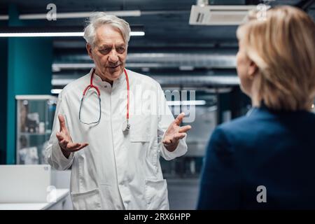 Medico anziano gestante e spiegazione al paziente in clinica Foto Stock