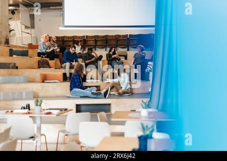 Team aziendale eterogeneo e multiculturale che discute, condivide idee e scrive appunti durante le riunioni. Concetto di brainstorming. Foto Stock