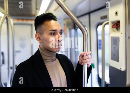 Uomo contemplativo in piedi sul treno Foto Stock