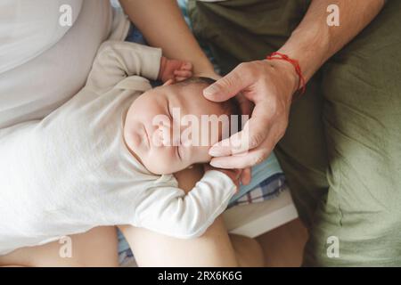 Un uomo con una figlia appena nata che dorme in braccio alla madre a casa Foto Stock