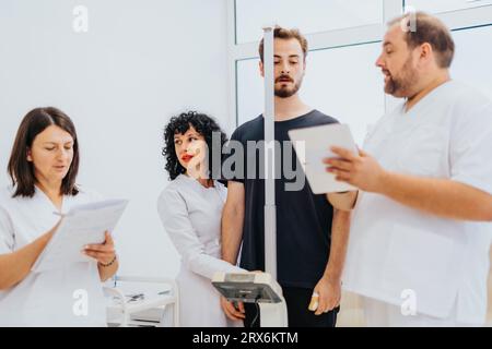 Medici esperti e professionisti sanitari in una sala ospedaliera affollata che fornisce assistenza e conduce visite mediche con un'atmosfera di supporto Foto Stock