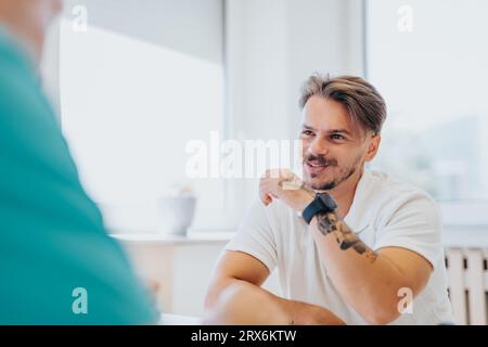 Medici esperti che analizzano i risultati medici e consigliano giovane paziente maschile Foto Stock