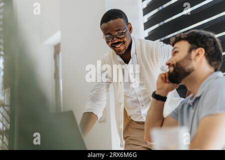 Razza mista, compagni di squadra maschili che lavorano insieme a un nuovo progetto in un'atmosfera positiva, discutendo, divertendosi e sorridendo. Foto Stock