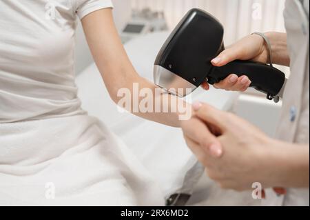 Cosmetologo che rimuove i capelli con il laser sulla mano della donna Foto Stock