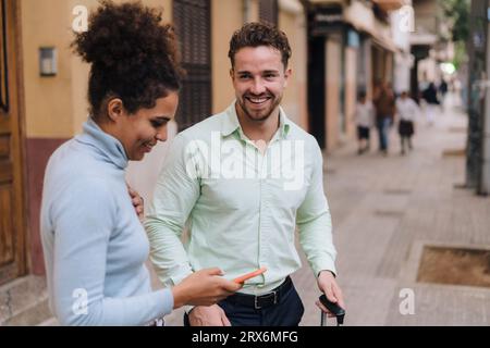 Un uomo d'affari felice con un collega che usa lo smartphone sul sentiero Foto Stock