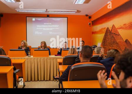 Sala conferenze piena di giovani studenti e vecchi professori che applaudono Foto Stock