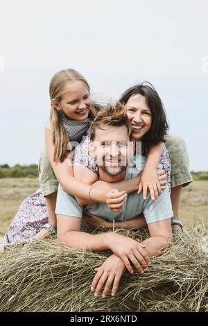 Famiglia felice sul fieno nel campo sotto il cielo Foto Stock