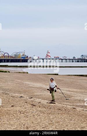 Donna metal detector lungo la spiaggia a Clacton on Sea. Foto Stock