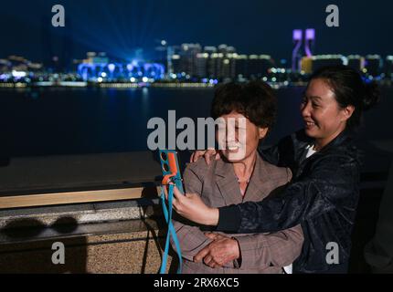 Hangzhou. 23 settembre 2023. La gente scatta selfie contro la vista notturna di Hangzhou, nella provincia orientale dello Zhejiang, 23 settembre 2023 Credit: Sun Fei/Xinhua/Alamy Live News Foto Stock