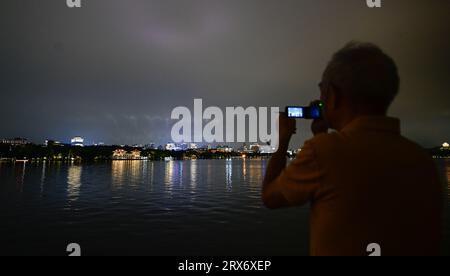 Hangzhou. 23 settembre 2023. Un uomo prende un video della vista notturna di Hangzhou, nella provincia di Zhejiang, nella Cina orientale, 23 settembre 2023 Credit: Yan Linyun/Xinhua/Alamy Live News Foto Stock