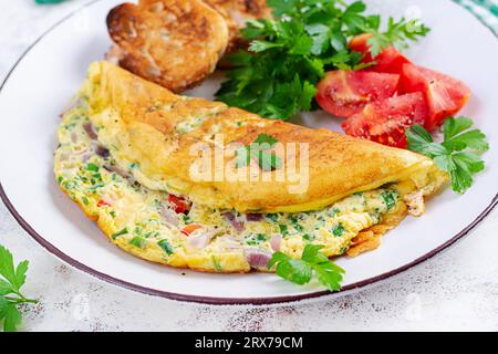 Omelette con pomodori, formaggio e cipolla rossa su piatto bianco. Frittata - omelette italiane. Foto Stock