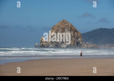 Cannon Beach Oregon USA - 21 agosto 2023 - Una donna che visita la roccia Haystack lungo la costa si affaccia sull'Oceano Pacifico Foto Stock