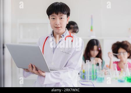 Ritratto giovane asiatico cinese intelligente cappotto bianco waring gioco di ruolo medico moderno con computer portatile e amico Foto Stock