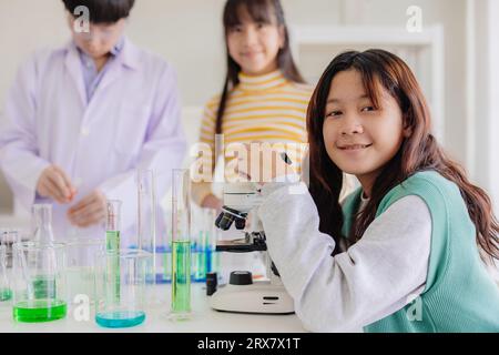 Ritratto giovane ragazza asiatica intelligente ama imparare e giocare in laboratorio di scienza chimica sperimentale a scuola sorridendo felice Foto Stock