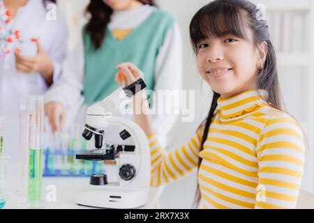 Ritratto giovane ragazza asiatica intelligente ama imparare e giocare in laboratorio di scienza chimica sperimentale a scuola sorridendo felice Foto Stock