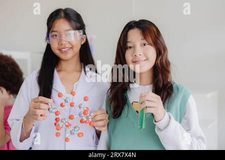 Ritratto giovane ragazza asiatica intelligente ama imparare e giocare in laboratorio di scienza chimica sperimentale a scuola sorridendo felice Foto Stock