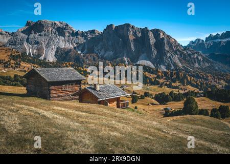 Graziose casette di legno sul pascolo di montagna e splendida cresta di montagna sullo sfondo, gruppo di Puez-Odle, Dolomiti, Italia, Europa Foto Stock