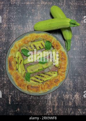 torta salata con zucchine e basilico su un piatto rotondo Foto Stock