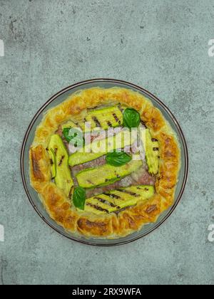 torta salata con zucchine e basilico su un piatto rotondo Foto Stock