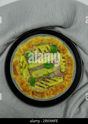 torta salata con zucchine e basilico su un piatto rotondo Foto Stock