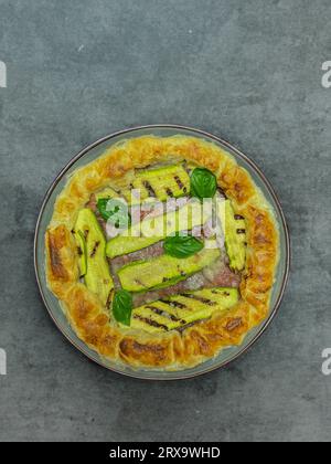 torta salata con zucchine e basilico su un piatto rotondo Foto Stock