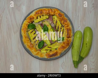 torta salata con zucchine e basilico su un piatto rotondo Foto Stock