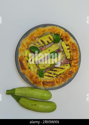 torta salata con zucchine e basilico su un piatto rotondo Foto Stock