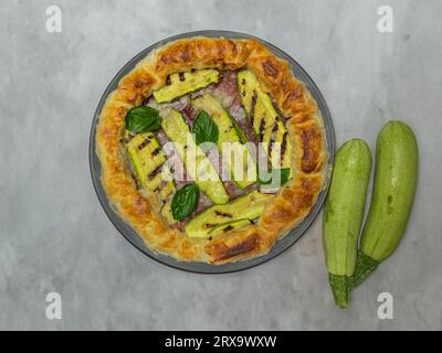 torta salata con zucchine e basilico su un piatto rotondo Foto Stock