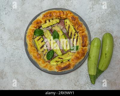 torta salata con zucchine e basilico su un piatto rotondo Foto Stock