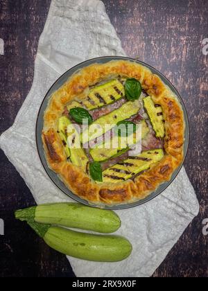 torta salata con zucchine e basilico su un piatto rotondo Foto Stock