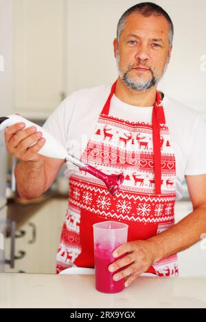 lo chef prepara il frullato a casa versando il frullato nel bicchiere dopo la cottura. Foto Stock