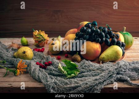 Natura morta autunnale con frutta, frutti di bosco e foglie autunnali su fondo di legno. Foto Stock