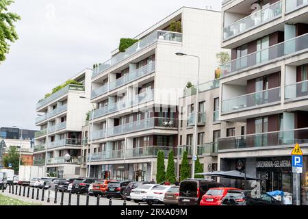 Nuovo appartamento. Strade della città. Edificio moderno. Quartiere residenziale di nuova costruzione. Piante cittadine europee sui balconi e sul tetto Parcheggio auto sotto l'edificio. Polonia, Varsavia - 26 luglio 2023 Foto Stock