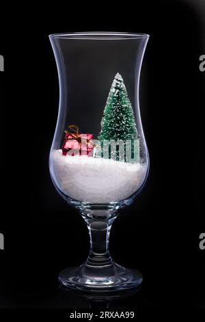 Un primo piano di un albero di natale e un regalo in un bicchiere di birra Foto Stock