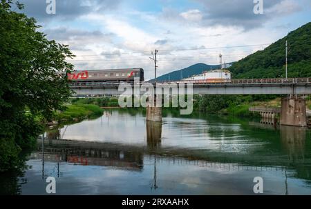 12 giugno 2023, Tuapse, Russia. Treno passeggeri della compagnia ferroviaria russa sul ponte ferroviario sul fiume. Foto Stock