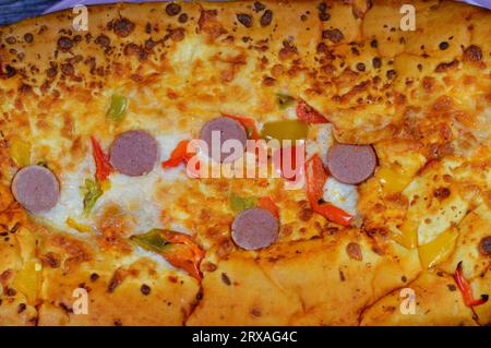 Formaggio Fougasse condito con fette di peperoni verdi, formaggio e salsiccia tagliata cotta in forno, il pane alla fougasse è un tipo di pane tipicamente associato Foto Stock