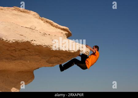 Un alpinista sale su un fungo calcareo nel deserto bianco, in Egitto Foto Stock