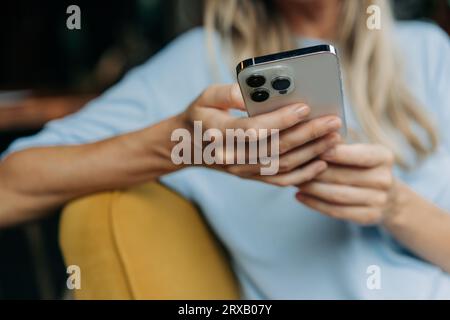 Una donna irriconoscibile scorre attraverso i social network e digita messaggi online sul suo telefono. Foto Stock