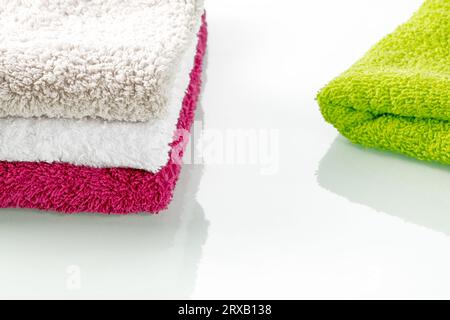 Accessori per il bagno. Una pila di morbidi asciugamani colorati di spugna su uno sfondo a specchio Foto Stock