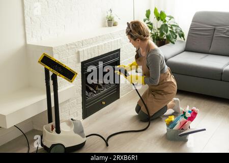 pulizia della casa. Ragazza spazzole vapore pulitori cucina bianco elettronico parabola vapore nei guanti. pulizia di una superficie. cucina leggera Foto Stock